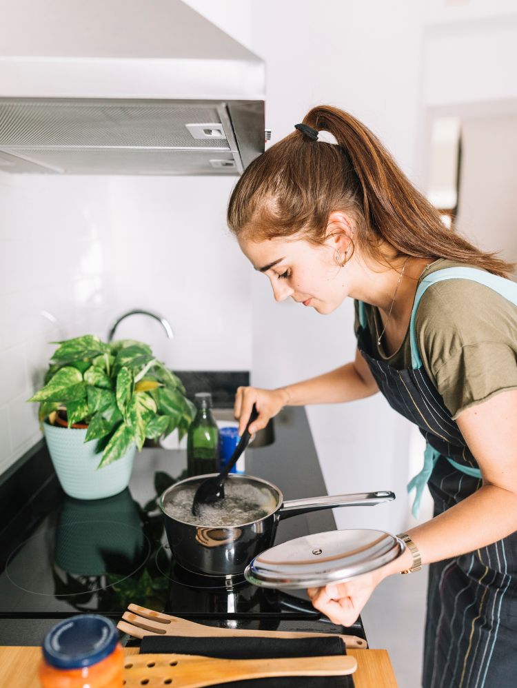 Moça loira cozinhando no cooktop de indução