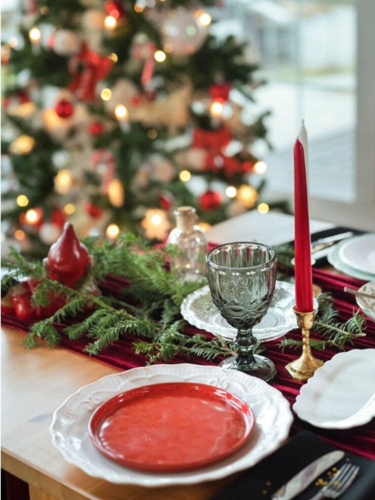 mesa posta com as cores do natal tradicional branco ,vermelho e verde com taças e velas.