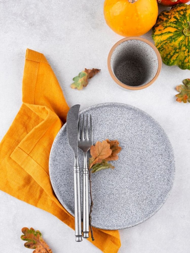 mesa posta com prato cinza granulado com o guardanapo amarelo bem alegre com copos e talheres. 