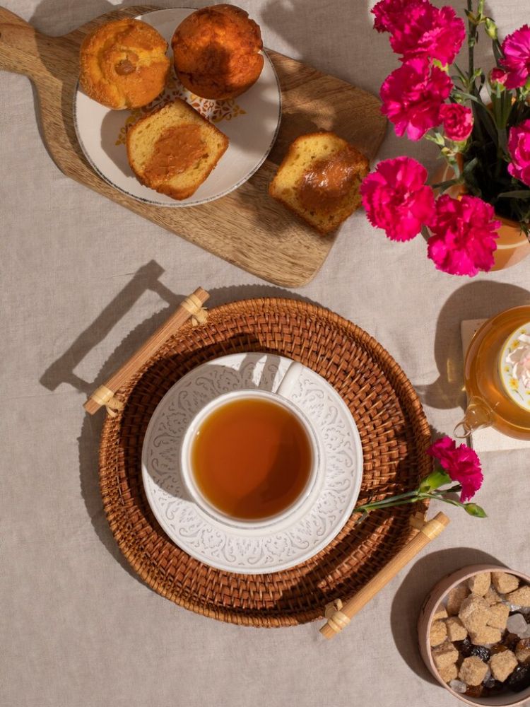 mesa posta para café da tarde com direito a bolinhos e chá com arranjo de flores rosa-do-deserto.